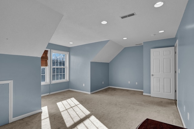 additional living space featuring light carpet and vaulted ceiling