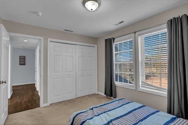 carpeted bedroom featuring a textured ceiling and a closet