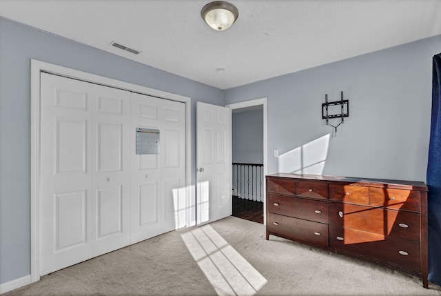 carpeted bedroom with a textured ceiling and a closet