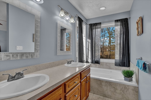 bathroom with ceiling fan, tile patterned floors, tiled bath, a textured ceiling, and vanity