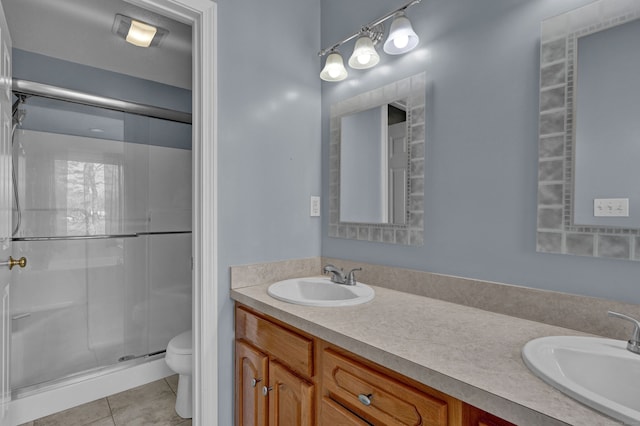 bathroom featuring tile patterned flooring, vanity, toilet, and a shower with door