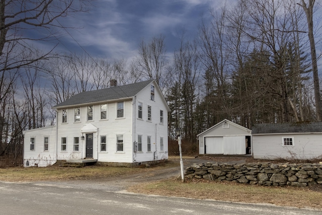 colonial-style house with a garage and an outdoor structure