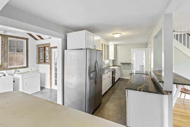 kitchen with white cabinetry, sink, independent washer and dryer, dark stone counters, and black appliances