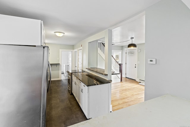 kitchen featuring white cabinetry, stainless steel appliances, hanging light fixtures, and a baseboard heating unit