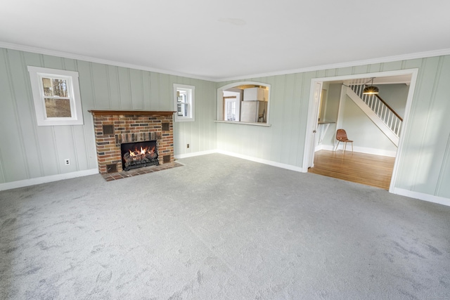 unfurnished living room with carpet, ornamental molding, and a brick fireplace