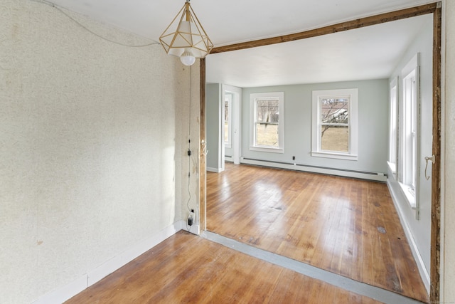 spare room with hardwood / wood-style flooring, plenty of natural light, and a baseboard heating unit