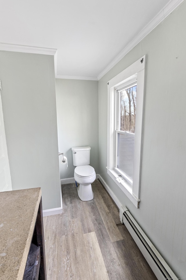 bathroom with hardwood / wood-style floors, a baseboard radiator, toilet, and crown molding