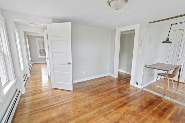 empty room with hardwood / wood-style floors and baseboard heating