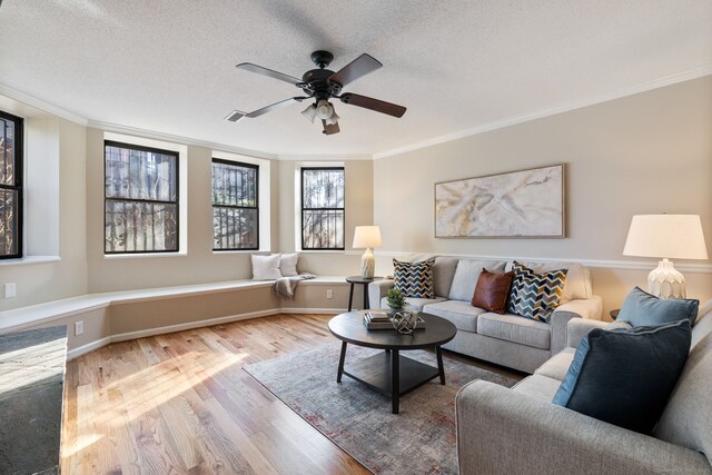 living room with baseboards, ceiling fan, ornamental molding, wood finished floors, and a textured ceiling