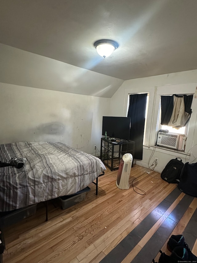 bedroom featuring hardwood / wood-style flooring, vaulted ceiling, and cooling unit