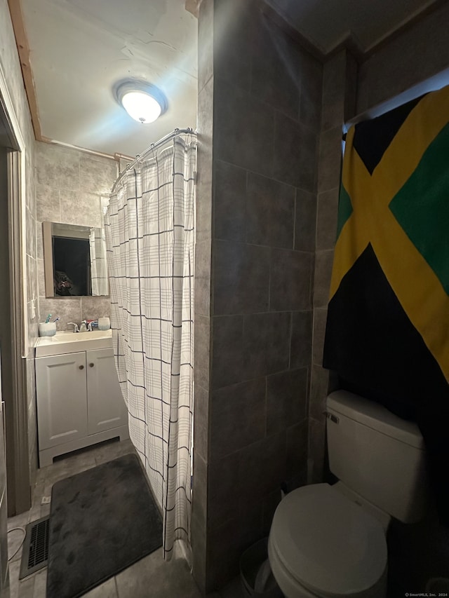 bathroom featuring vanity, tile walls, and toilet