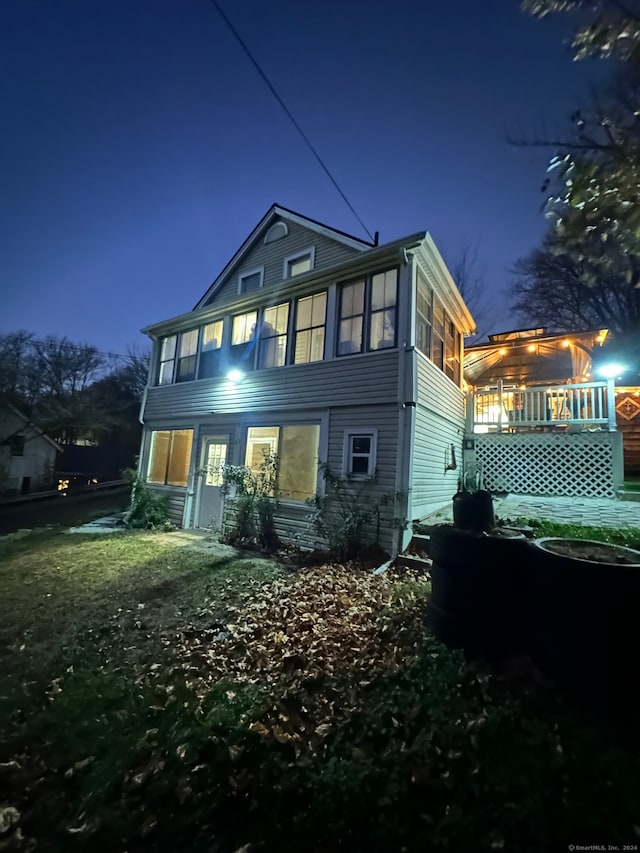 back house at twilight with a sunroom