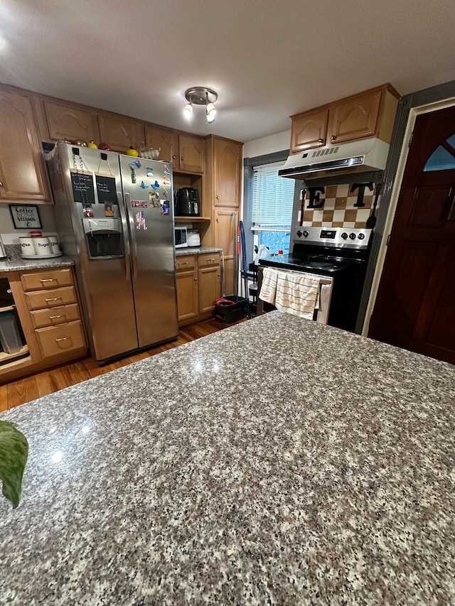 kitchen with light wood-type flooring, stainless steel appliances, and tasteful backsplash