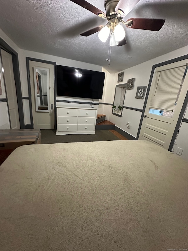 unfurnished bedroom featuring ceiling fan, a textured ceiling, and dark colored carpet