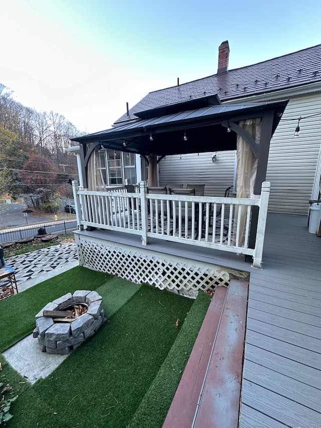 rear view of house featuring a lawn, a wooden deck, and a fire pit