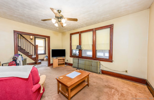 carpeted living room with ceiling fan and radiator heating unit