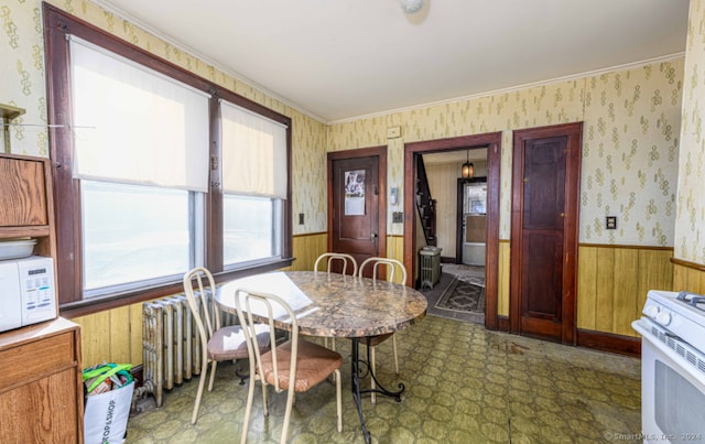 dining space featuring wooden walls and crown molding