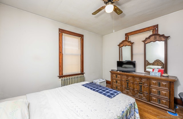 bedroom with radiator heating unit, ceiling fan, and hardwood / wood-style floors