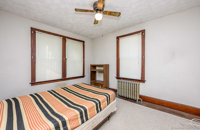 carpeted bedroom with ceiling fan, a textured ceiling, and radiator