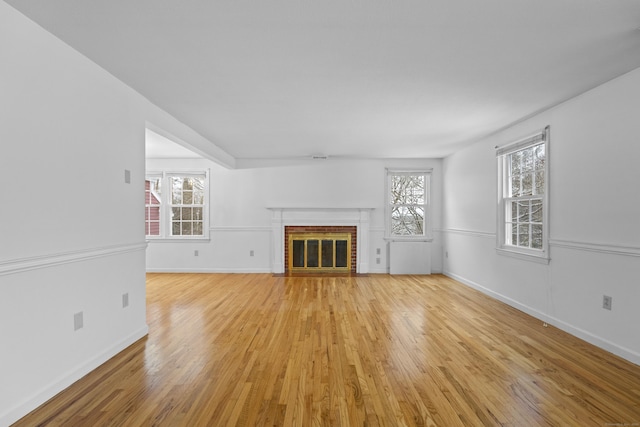 unfurnished living room featuring a fireplace, light hardwood / wood-style floors, and plenty of natural light