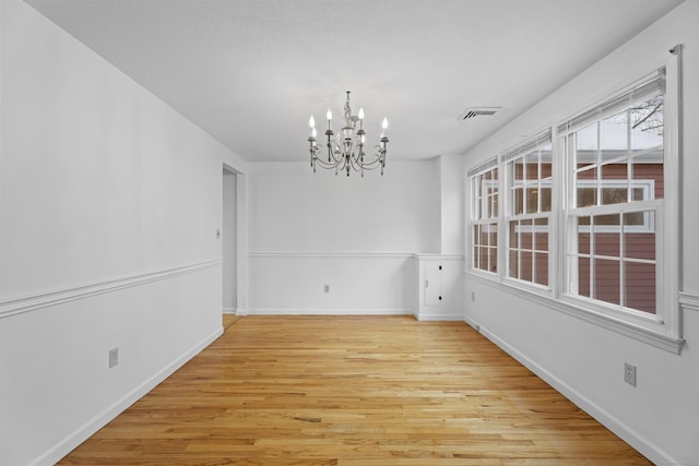 unfurnished dining area featuring light hardwood / wood-style floors and a chandelier