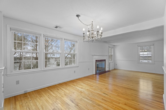 unfurnished living room featuring hardwood / wood-style flooring and an inviting chandelier