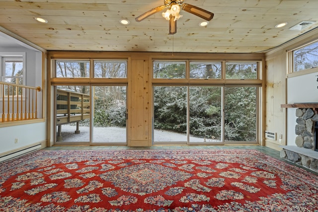 unfurnished living room with ceiling fan, a stone fireplace, plenty of natural light, and wood ceiling