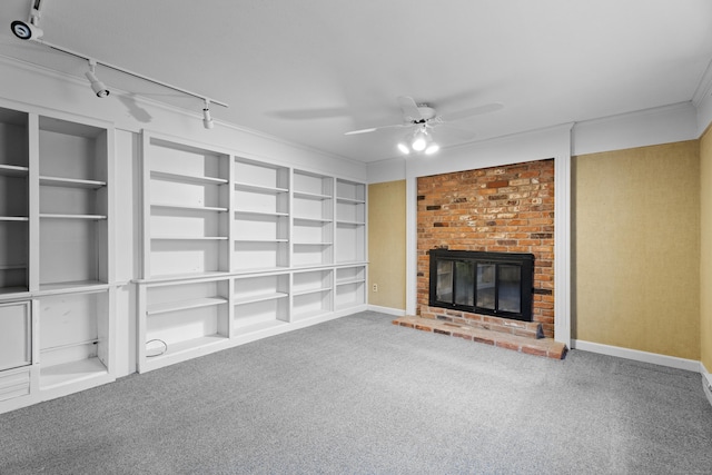 unfurnished living room featuring ceiling fan, rail lighting, built in features, carpet floors, and a fireplace