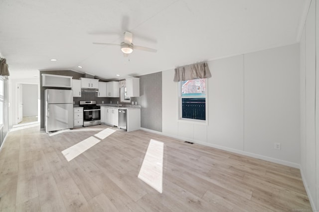 kitchen featuring vaulted ceiling, white cabinetry, stainless steel appliances, and light hardwood / wood-style flooring