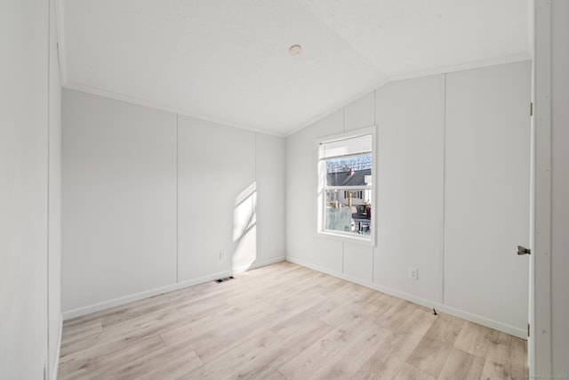 unfurnished room featuring light hardwood / wood-style flooring, vaulted ceiling, and ornamental molding