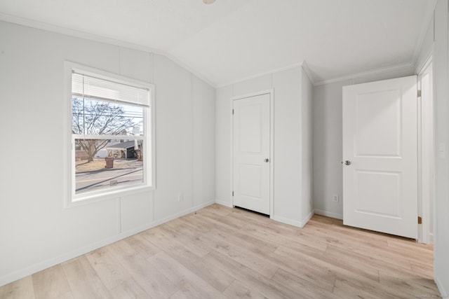 interior space with light wood-type flooring, vaulted ceiling, and ornamental molding