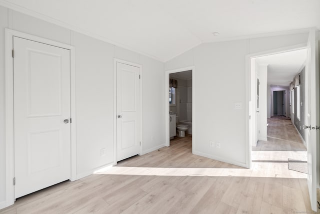 unfurnished bedroom with connected bathroom, light hardwood / wood-style floors, and lofted ceiling