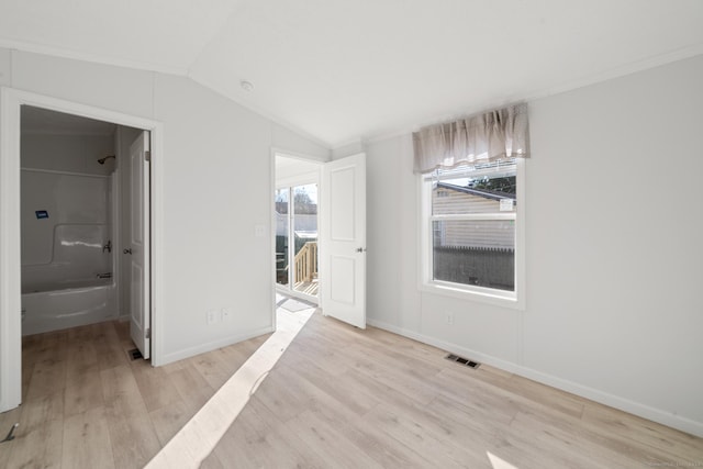 empty room with a wealth of natural light, light hardwood / wood-style flooring, and lofted ceiling