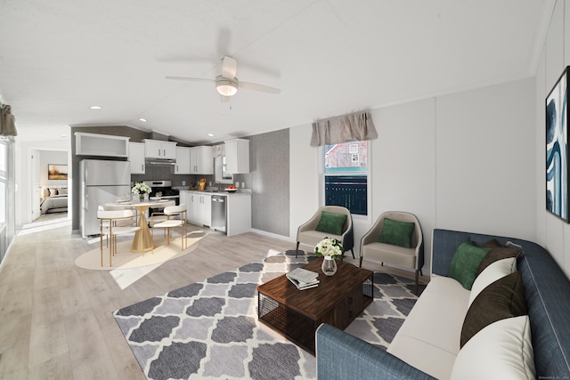 living room with ceiling fan, sink, light hardwood / wood-style floors, and vaulted ceiling