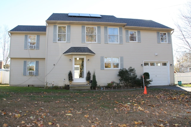 view of front facade with solar panels, cooling unit, a front yard, and a garage