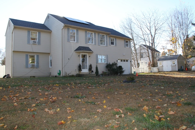 colonial house with solar panels, cooling unit, a front lawn, a storage unit, and a garage