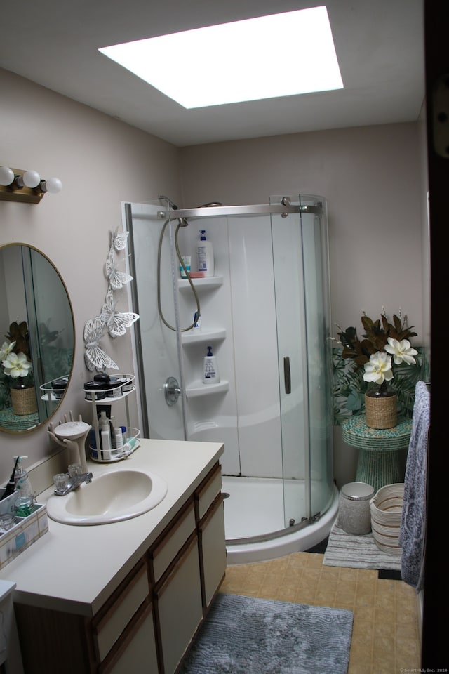 bathroom featuring tile patterned flooring, vanity, a shower with door, and a skylight