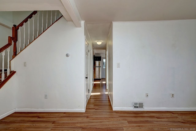 empty room featuring beam ceiling and light wood-type flooring