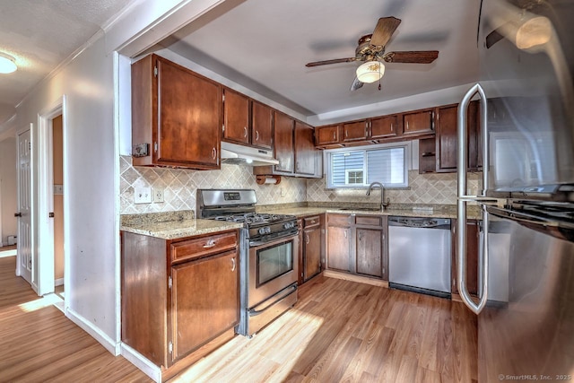 kitchen featuring tasteful backsplash, stainless steel appliances, sink, and light hardwood / wood-style flooring