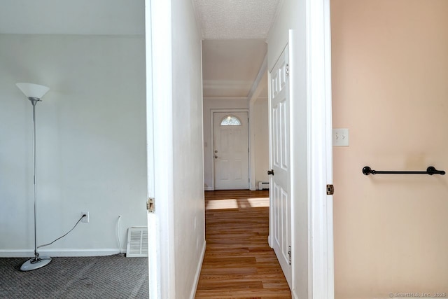 hall with a textured ceiling and light hardwood / wood-style flooring