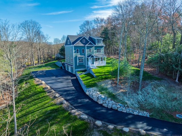 view of front of property featuring covered porch, a garage, and a front yard