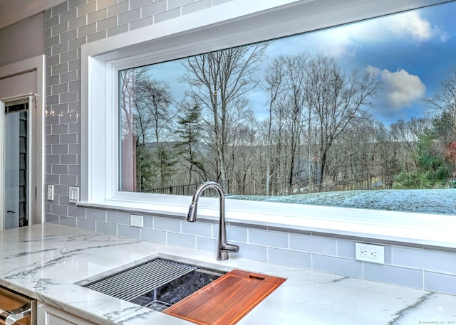 interior details featuring light stone countertops, sink, and dishwasher