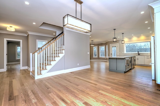 kitchen with pendant lighting, gray cabinetry, a center island, light wood-type flooring, and white cabinetry