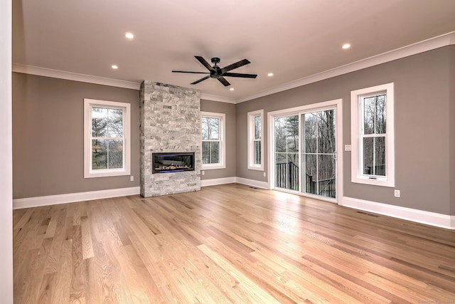 unfurnished living room with ceiling fan, light hardwood / wood-style floors, ornamental molding, and a fireplace