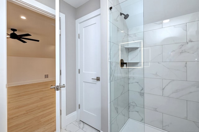 bathroom with a tile shower and ceiling fan