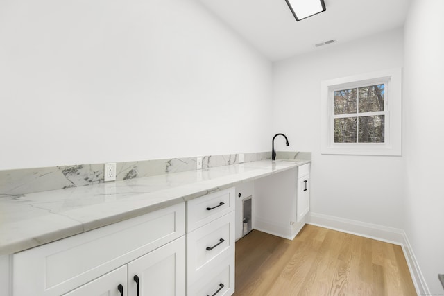 clothes washing area with light hardwood / wood-style flooring and sink