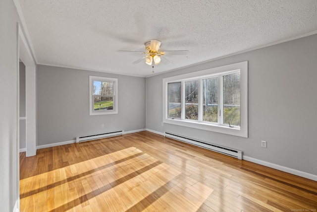 empty room featuring a textured ceiling, light hardwood / wood-style flooring, and a baseboard heating unit