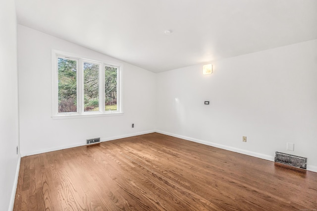 spare room featuring wood-type flooring and vaulted ceiling