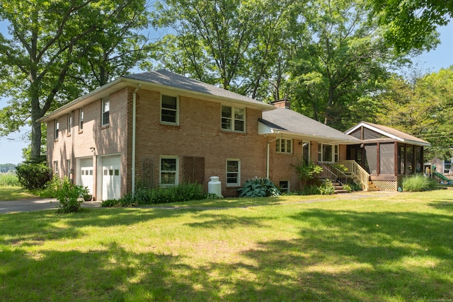 view of front of home with a sunroom, a garage, and a front lawn