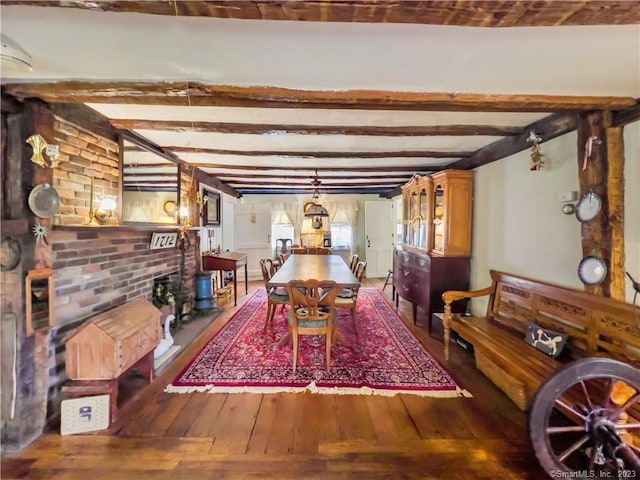 dining space with beam ceiling, a fireplace, dark hardwood / wood-style flooring, and brick wall